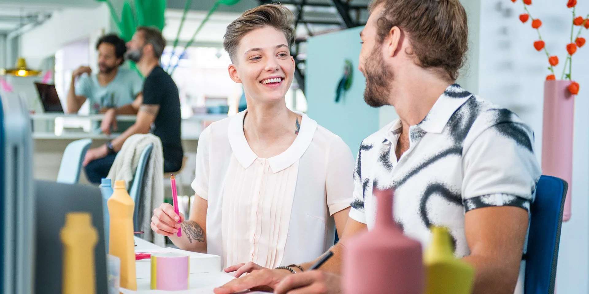 Zwei junge Auszubildende im Gespräch an einem hellen Arbeitsplatz