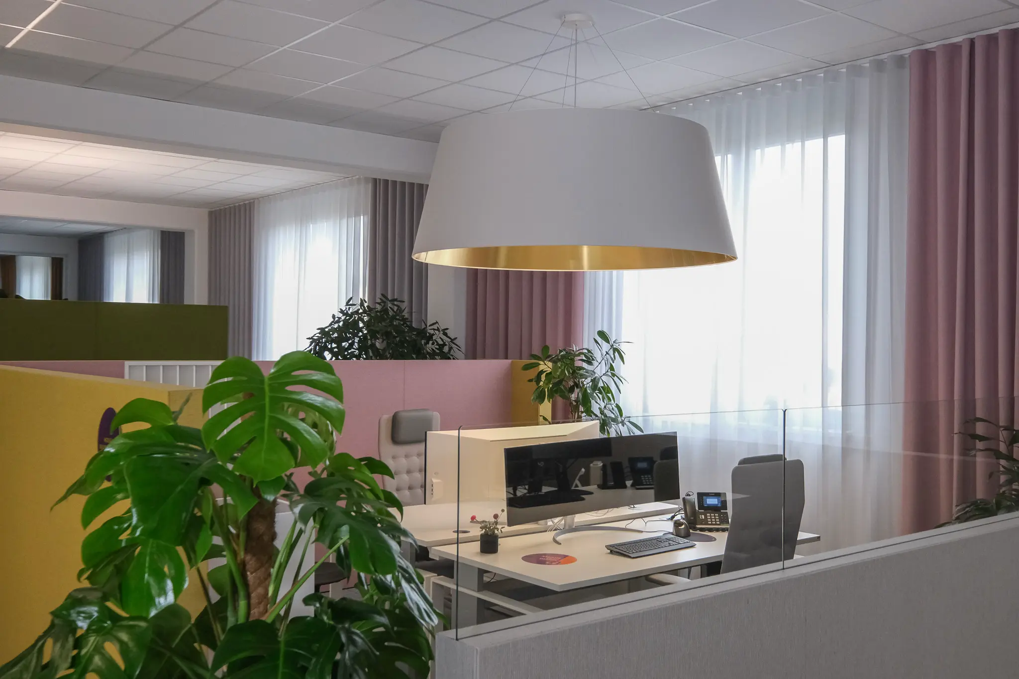 Arbeitsplatz unter einer großen Pendelleuchte mit goldenem Innenschirm