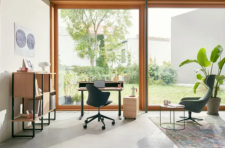 Homeoffice-Arbeitsplatz mit Schreibtisch und Loungesessel vor der Gartentür