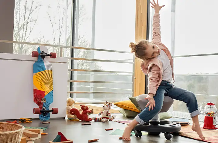 Kind sitzt auf einem beweglichen Kinderdrehhocker im Spielzimmer