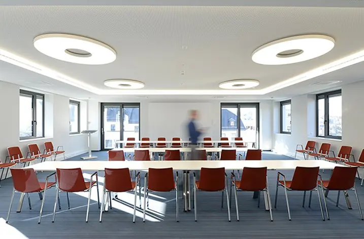Konferenzraum mit roten Stapelstühlen unter runden Deckenleuchten