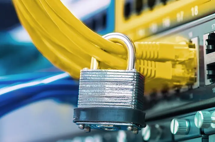 Vorhängeschloss vor gelben Netzwerkkabeln an einem Switch