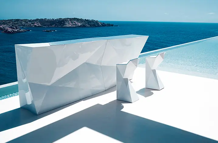 Weiße Outdoor-Bar mit zwei Hockern auf einer Terrasse am Meer