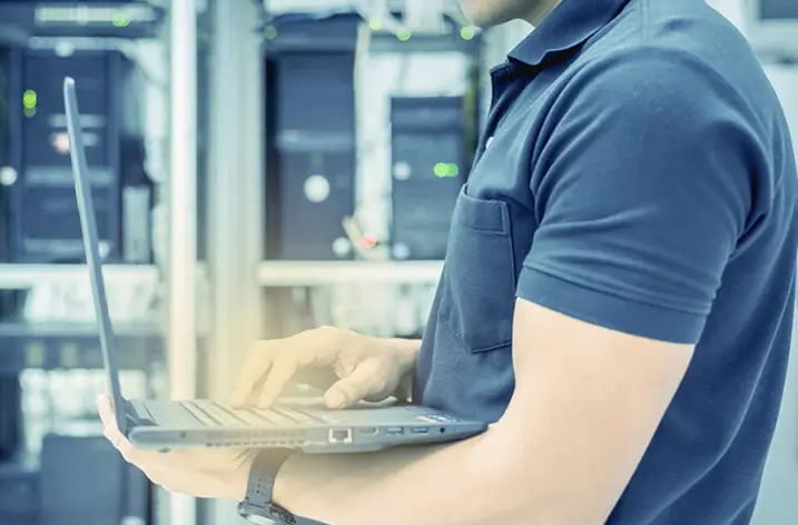 Servicetechniker mit Notebook vor einem Serverschrank