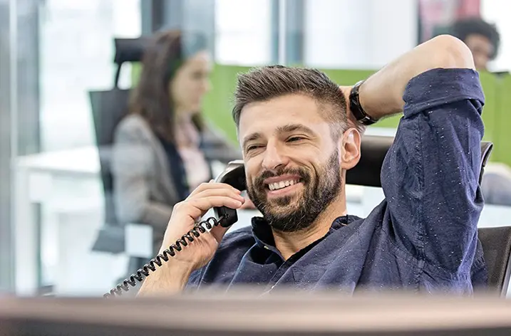 Mitarbeiter telefoniert entspannt zurückgelehnt am Arbeitsplatz