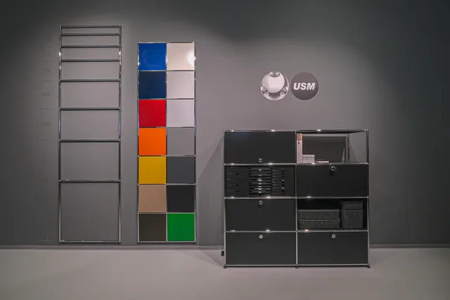 USM-Ausstellung mit Chromgestell, Farbtafel der Frontblenden und schwarzem Sideboard